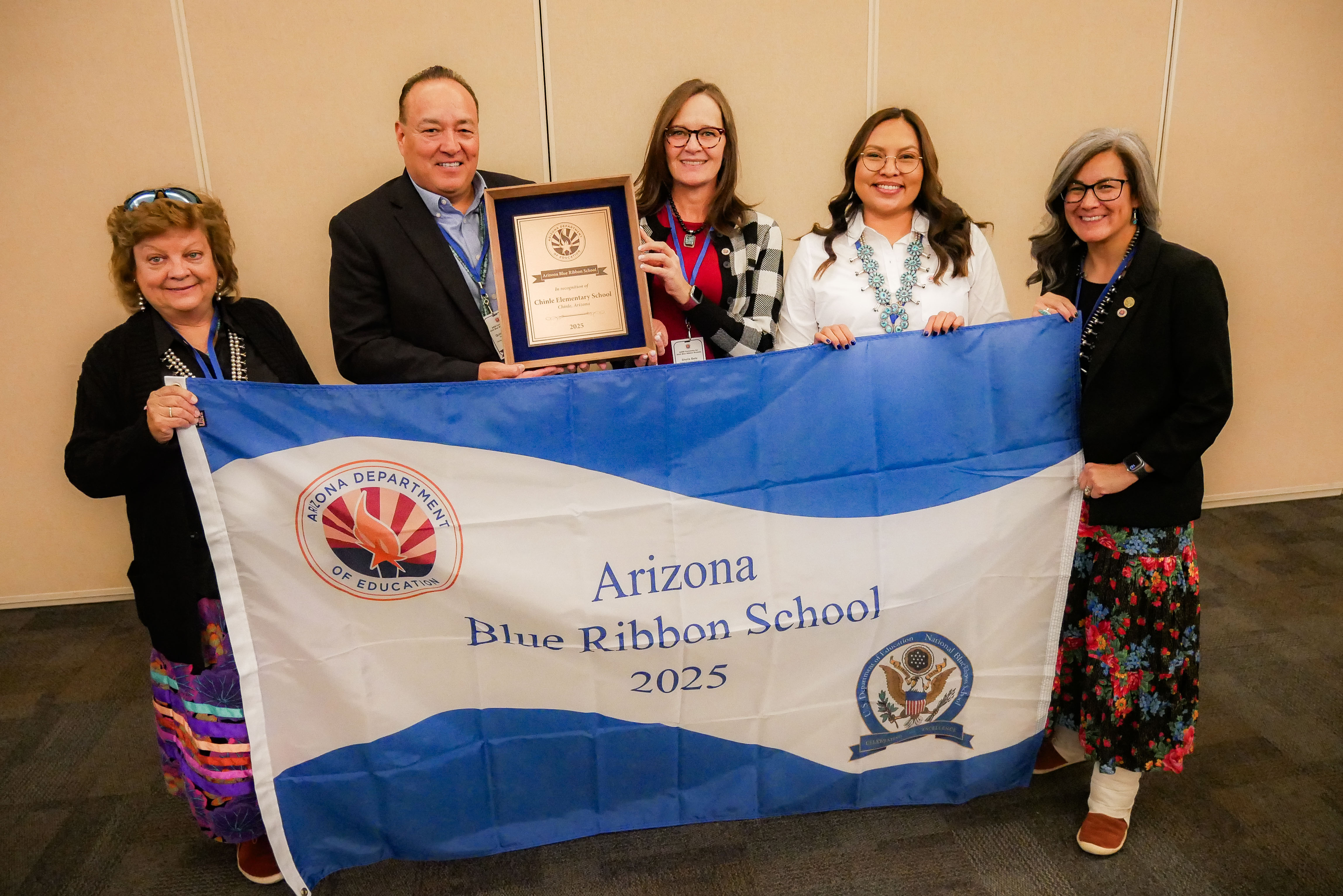 Staff from Chinle Elementary school pose with Blue Ribbon School 2025 Banner and plaque