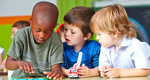 black preschool boy playing with letters with two preschool boys